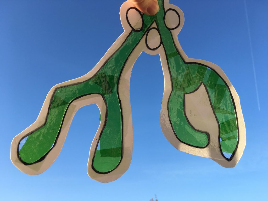 handmade Mistletoe sun catcher against a blue sky