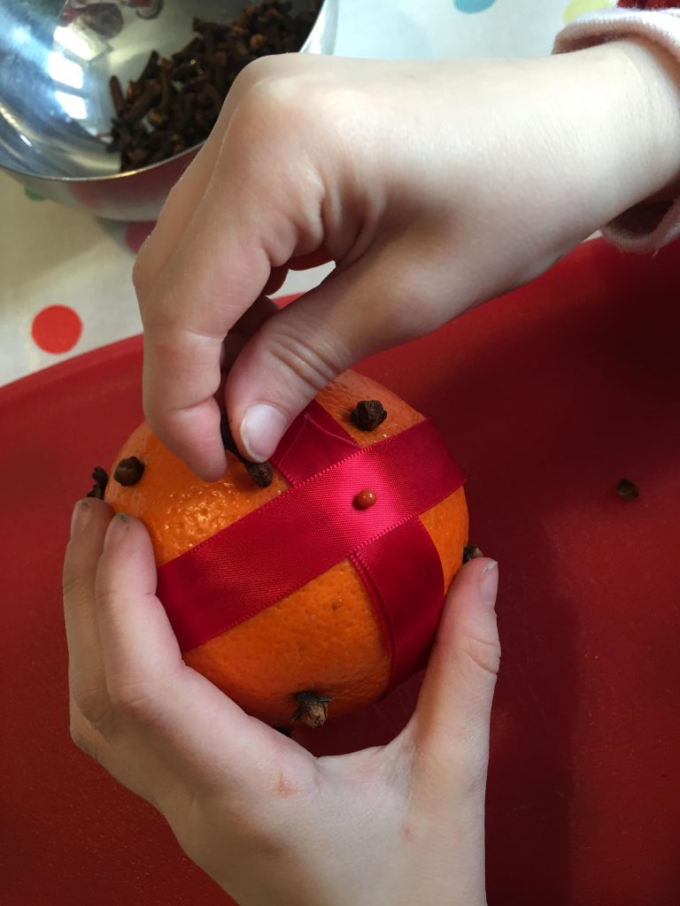 placing cloves in an orange